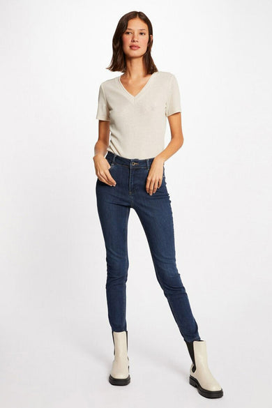 T-shirt beige à manches courtes de Morgan De Toi, avec col V, porté avec des jeans noirs et des bottes crème.
