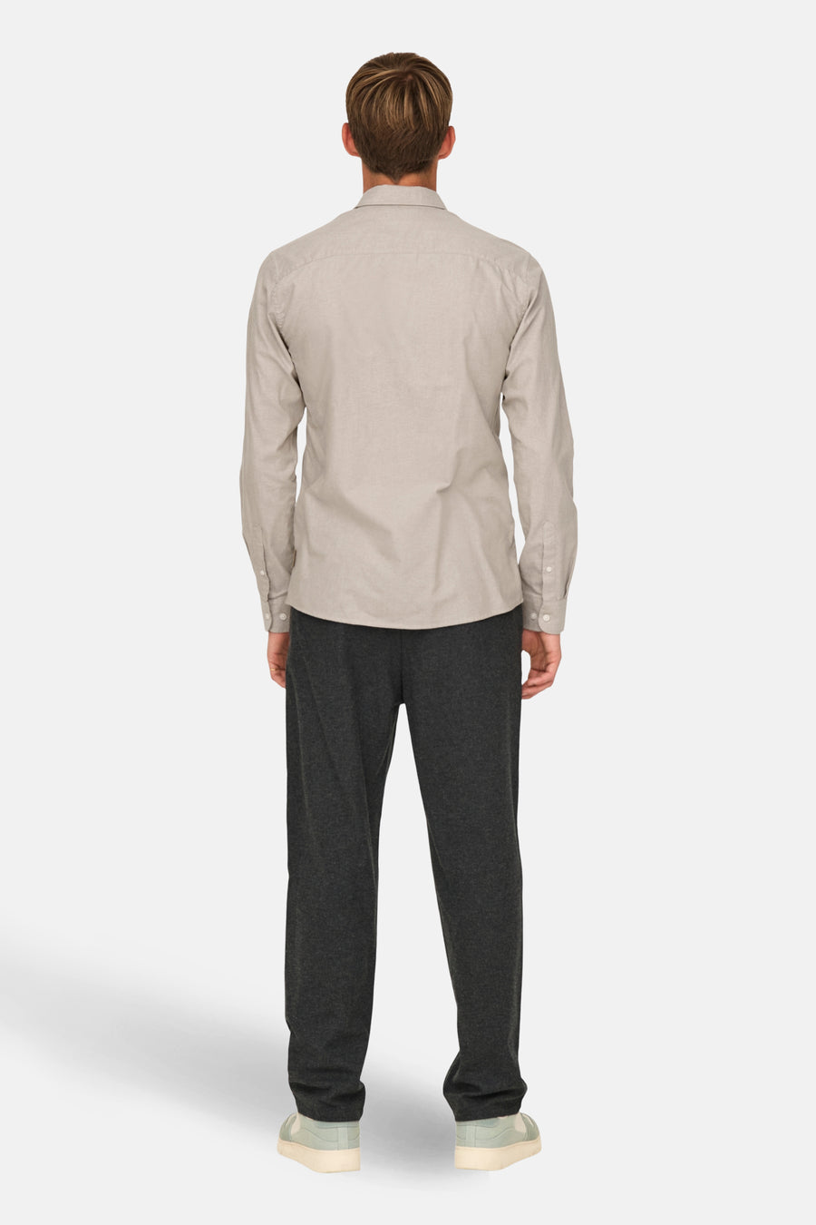 Achterkant van een man in een beige overhemd en grijze broek.