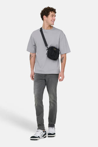 Grijze slim fit jeans van ONLY & SONS®, met een subtiele wassing en gecombineerd met een grijze t-shirt en zwarte schoudertas.
