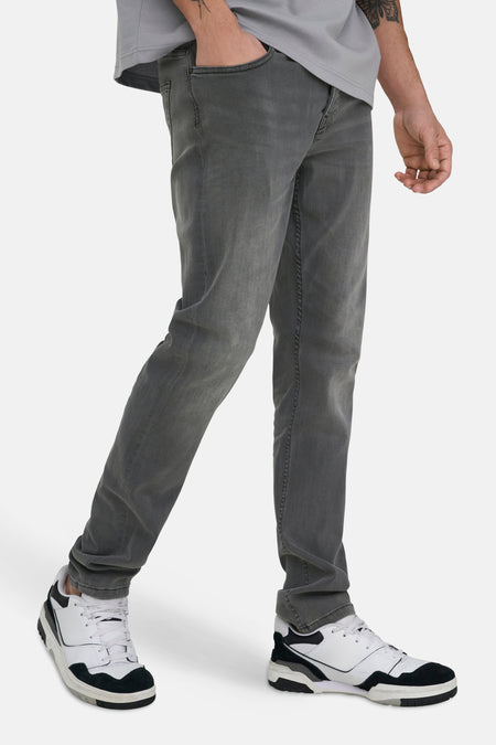 Donkergrijze slim fit jeans van ONLY & SONS®, met gedragen wassing en gecombineerd met witte sneakers.