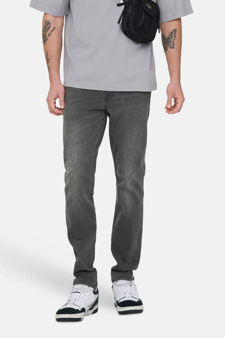Donkergrijze slim fit jeans van ONLY & SONS, met subtiele wassing en gecombineerd met een grijs T-shirt en schoudertas.