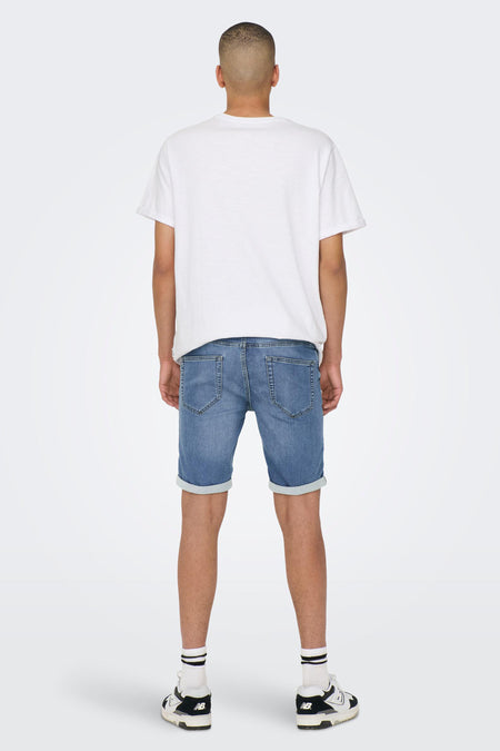 Jeansshort in lichtblauwe denim van ONLY & SONS, met omgeslagen zoom en witte sokken met zwarte strepen.
