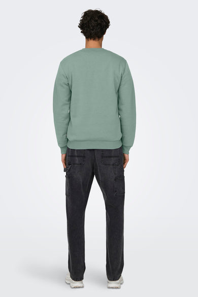 Groene sweater met ronde hals van ONLY & SONS®, achterzijde zichtbaar, gedragen met donkere jeans en witte sneakers.