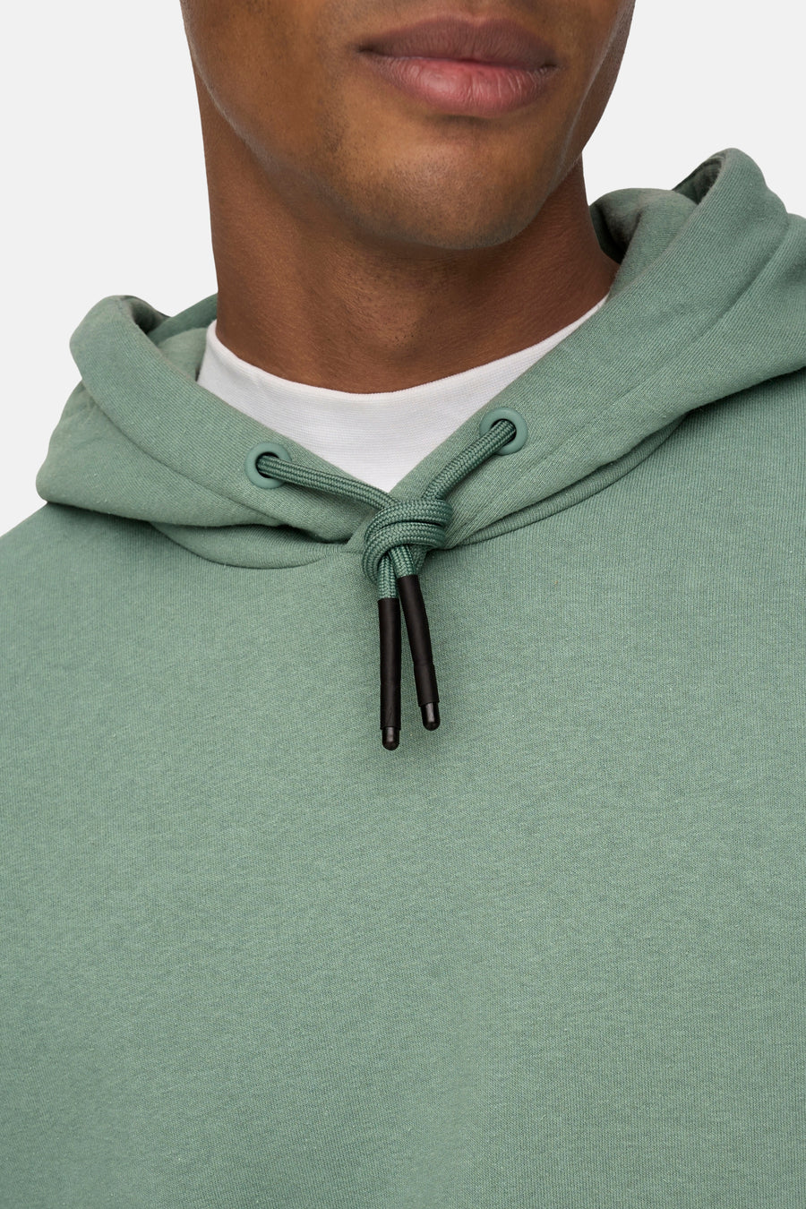 Pull-over vert de ONLY & SONS avec capuche, avec des boutons-pression noirs, porté sur un T-shirt blanc.