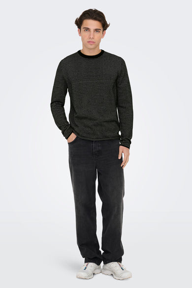 Pull noir à col rond de ONLY & SONS® avec un motif de petits pois blancs, porté avec un jean foncé et des baskets blanches, vue de face.