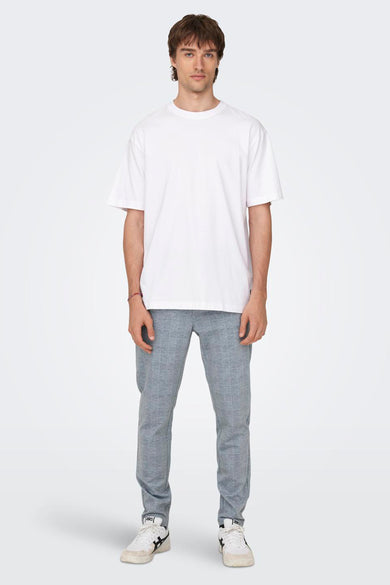 T-shirt blanc d'ONLY & SONS®, à manches courtes, associé à un pantalon large et des baskets blanches.