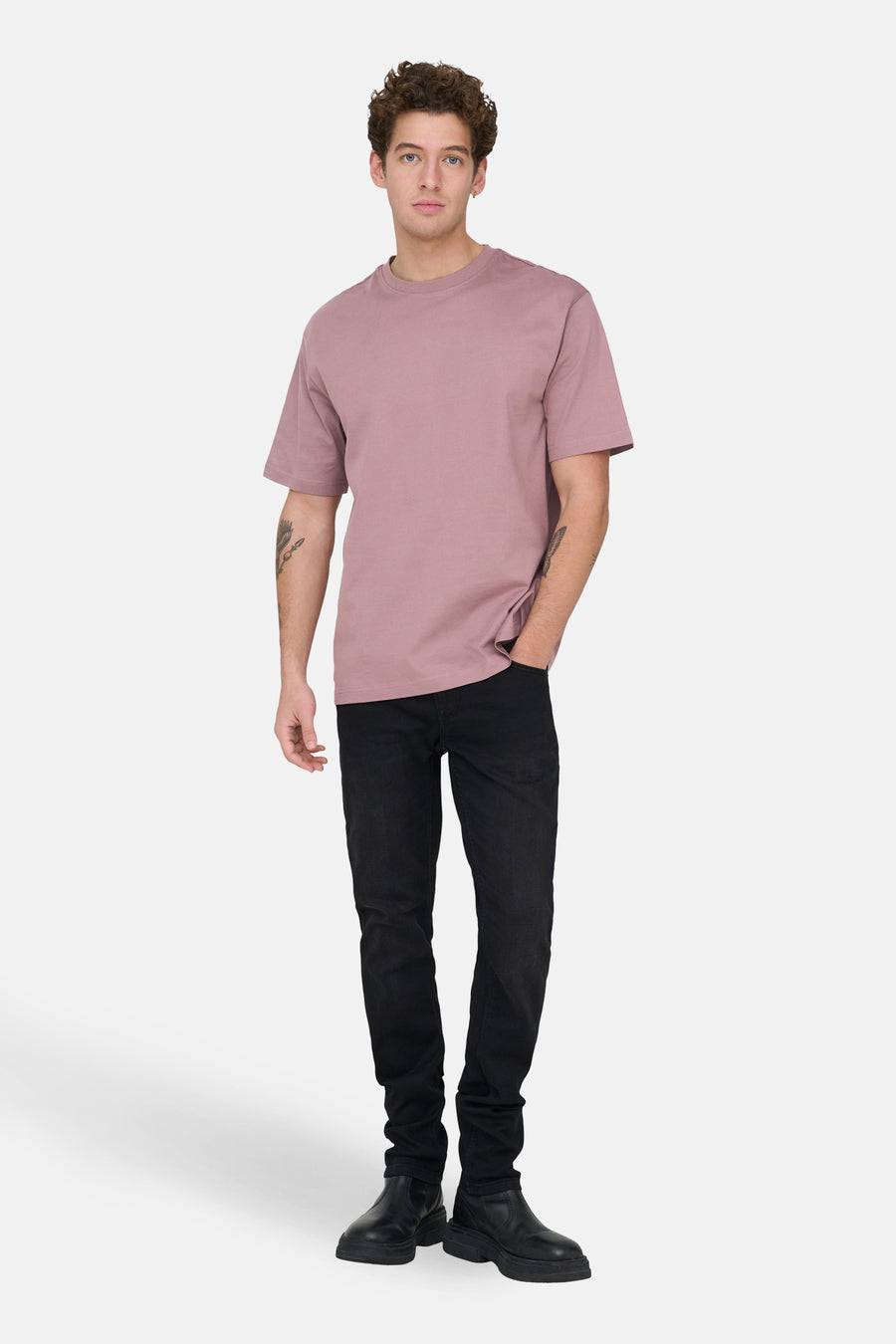 T-shirt rose à manches courtes de ONLY & SONS, porté avec des jeans noirs et des bottes en cuir.