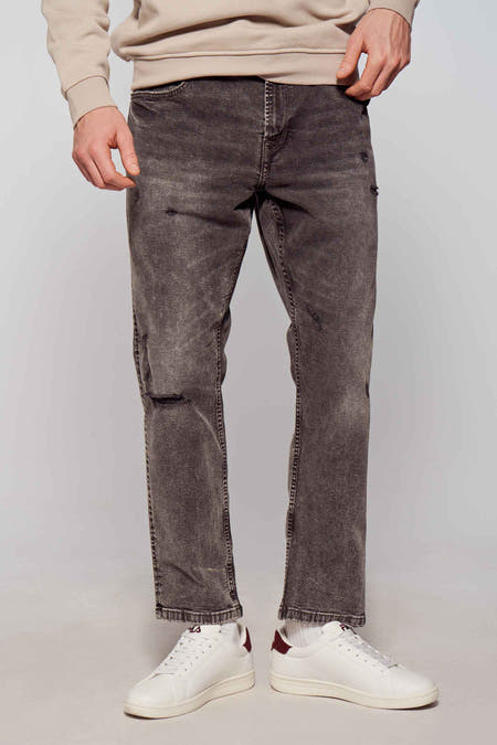 Jean tapered en denim gris foncé de ONLY & SONS, avec des déchirures et des baskets blanches.