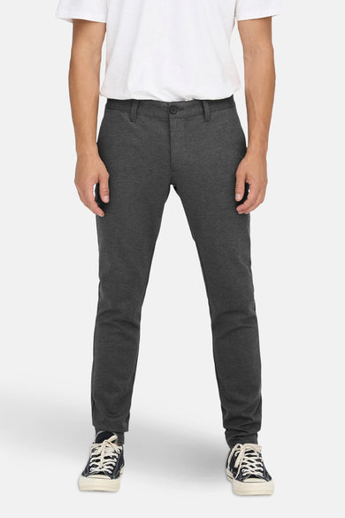 Pantalon gris de ONLY & SONS®, avec un design simple, associé à un t-shirt blanc et des baskets noires.