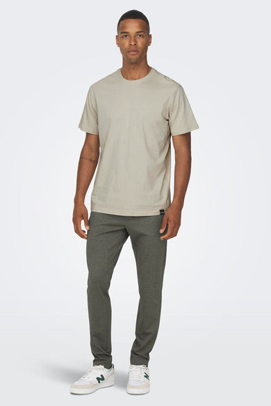 Bruine broek van ONLY & SONS, met een subtiele textuur en gecombineerd met een beige T-shirt en witte sneakers.

