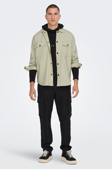 Chemise grise à manches longues de ONLY & SONS®, portée sur une hoodie noire et un pantalon cargo noir.