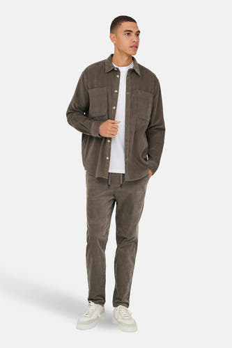 Bruin hemd van ONLY & SONS®, met lange mouwen, gedragen over een wit T-shirt en een bijpassende broek.