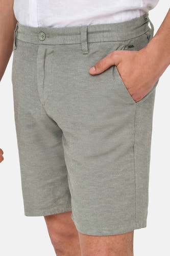 Grijze short van ONLY & SONS, met hand in de zak, onderdeel van een outfit met wit overhemd.
