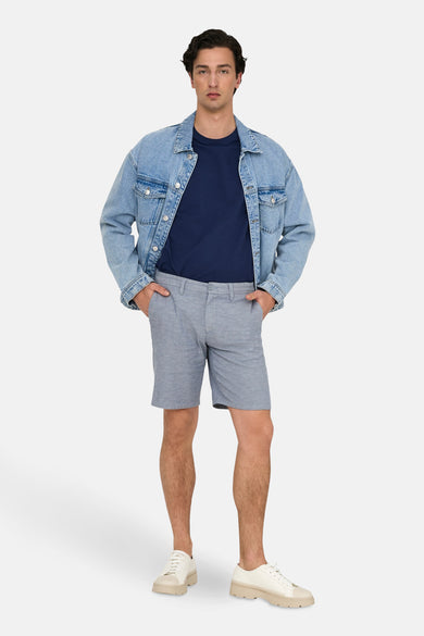 Blauwe short van ONLY & SONS, gecombineerd met een donkerblauw shirt en een spijkerjas.