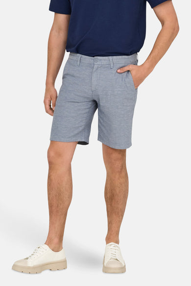 Blauwe short van ONLY & SONS, gedragen met een donkerblauw poloshirt en witte sneakers.
