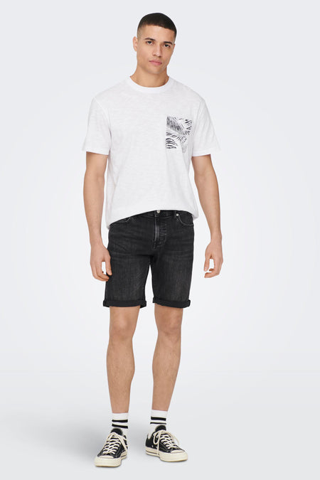 Zwarte denim jeansshort van ONLY & SONS, met opgerolde pijpen en gecombineerd met een wit t-shirt en zwarte sneakers met sokken.