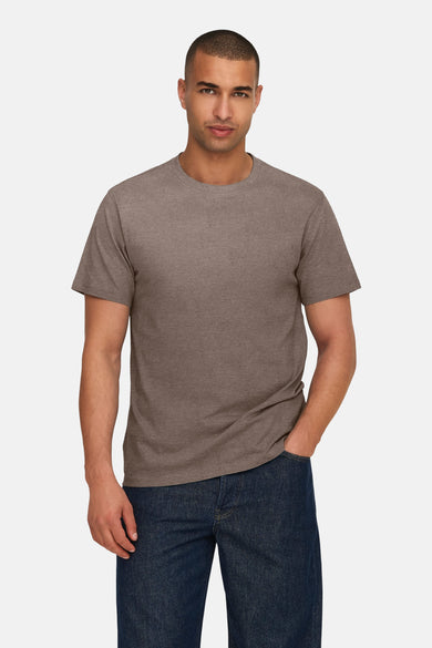 Bruin T-shirt met korte mouwen van ONLY & SONS®, gedragen met donkere jeans en één hand in de zak.
