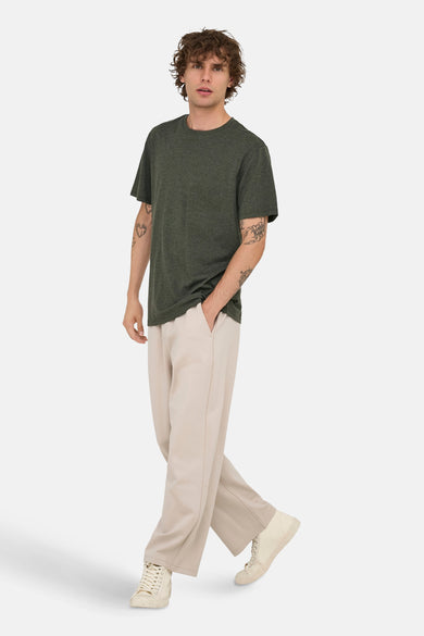 Groen T-shirt met korte mouwen van ONLY & SONS, met tattoos op de armen, gedragen met beige broek en crèmekleurige hoge sneakers.