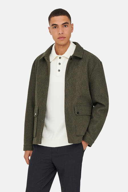 Manteau brun court de ONLY & SONS®, avec des poches et porté sur un chemisier blanc et un pantalon foncé.