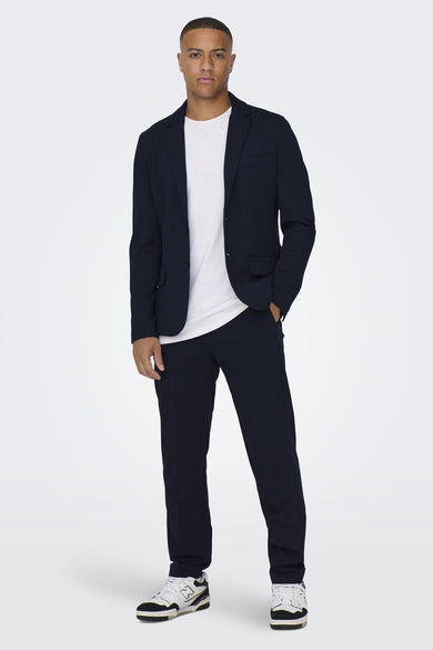 Blauwe blazer van ONLY & SONS, gedragen over een wit T-shirt en een broek met sneakers.
