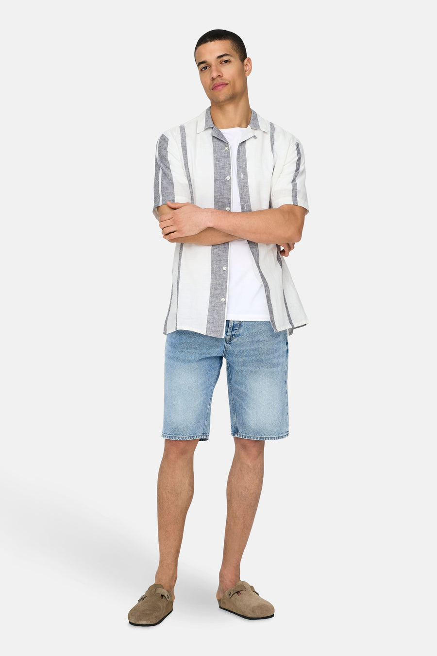 Ecrukleurig overhemd met korte mouwen van ONLY & SONS® met verticale strepen, gedragen over een wit T-shirt en lichtblauwe denim shorts.
