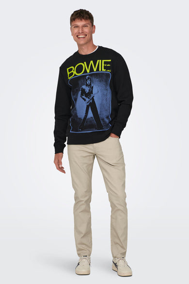 Zwarte sweater met ronde hals van ONLY & SONS, met David Bowie print op de voorkant, gecombineerd met kaki broek en sneakers.
