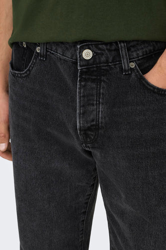 Zwarte jeans met merkknop en hand in zak.