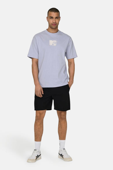 Zwarte short van ONLY & SONS, gecombineerd met een lichtblauw T-shirt met MTV-logo en witte sneakers met zwarte details.