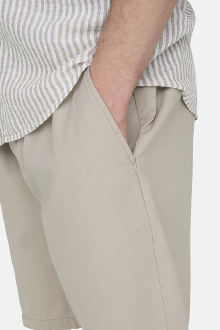 Beige court de ONLY & SONS, avec la main dans la poche et chemise rayée.