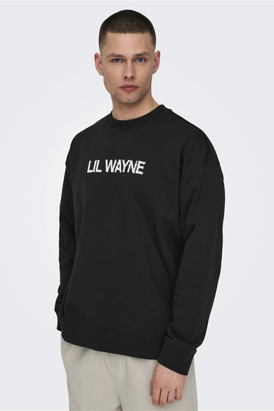 Zwarte sweater van ONLY & SONS met witte "Lil Wayne" tekstprint op de borst, gecombineerd met een beige broek.
