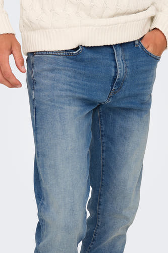 Lichtblauwe straight jeans van ONLY & SONS®, met hand in de zak, gedragen met een witte kabeltrui.
