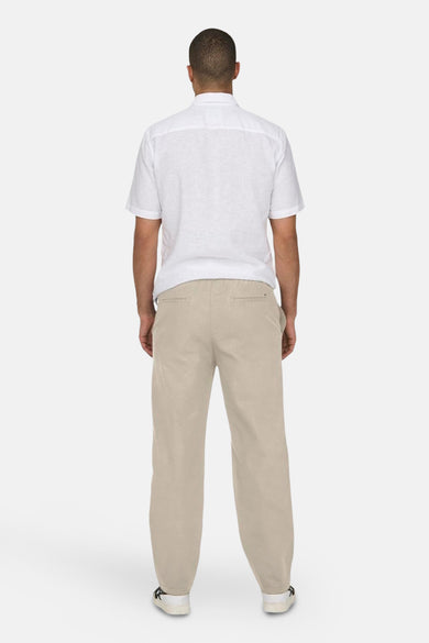 Ecru broek van ONLY & SONS, gezien van achteren, met een witte blouse en schoenen.
