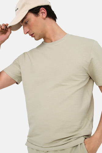 Beige T-shirt met korte mouwen van ONLY & SONS®, met een wafeltextuur en gedragen met een pet.
