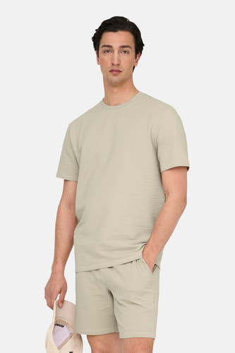 Beige T-shirt met korte mouwen van ONLY & SONS®, gemaakt van een geweven stof, gedragen met bijpassende shorts.