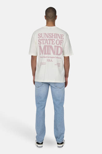 T-shirt beige à manches courtes de ONLY & SONS®, avec une impression rose et porté avec un jean bleu.