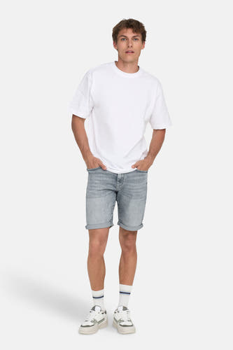 Jeansshort in lichtgrijs denim van ONLY & SONS®, met opgerolde pijpen, gecombineerd met een wit T-shirt en lage sneakers.