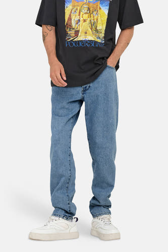 Jean fuselé en denim bleu clair de ONLY & SONS, avec des plis sur le devant et des baskets blanches.
