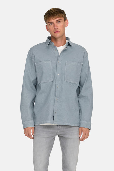 Lichtblauw denim overhemd met lange mouwen van ONLY & SONS, met witte stiksels, over een wit T-shirt, met grijze jeans.
