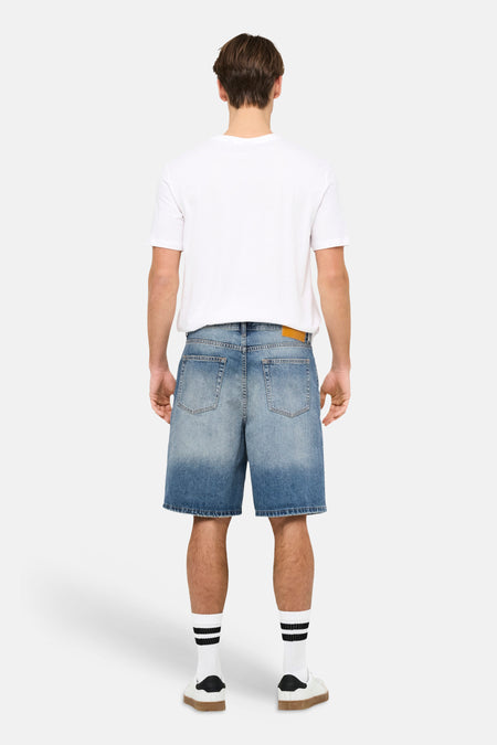 Short en jean bleu moyen de ONLY & SONS, avec poches arrière, porté avec des chaussettes blanches et des baskets.