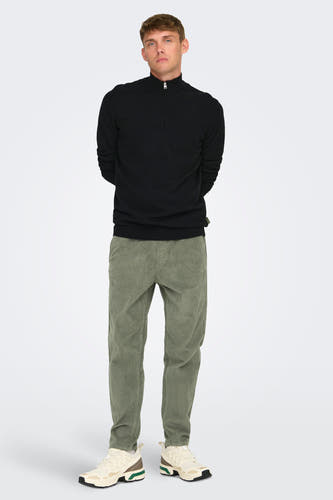 Grijze broek van ONLY & SONS®, met een ribstof textuur, gecombineerd met een zwarte trui en witte schoenen.
