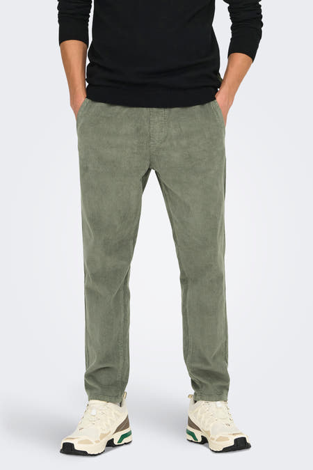 Pantalon gris d'ONLY & SONS®, en corduroy, associé à une chemise noire et des baskets crème.