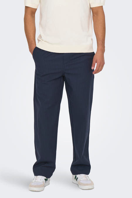 Blauwe broek met krijtstreep van ONLY & SONS®, gecombineerd met een ecrukleurige sweater en sneakers.
