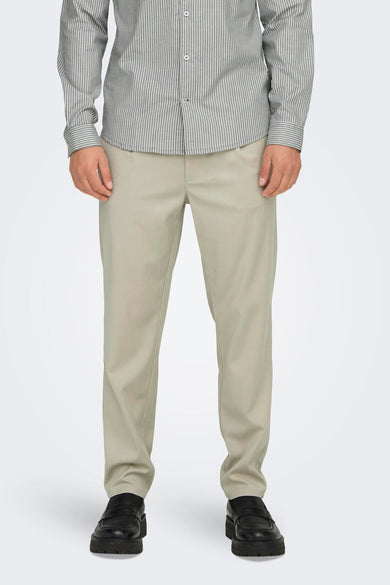 Ecru broek van ONLY & SONS, gecombineerd met een gestreept overhemd en zwarte loafers.
