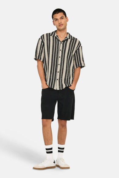 Chemise multicolore à manches courtes ONLY & SONS®, rayée et portée avec un short noir et des baskets blanches.