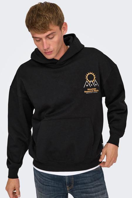 Zwarte sweater met kap van ONLY & SONS, met print op de borst, gedragen over een wit T-shirt en een blauwe jeans.
