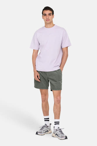Shorts kaki de ONLY & SONS, avec une texture côtelée, associés à un T-shirt violette et des baskets grises avec des chaussettes rayées.