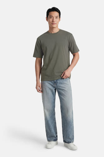 Groen T-shirt met korte mouwen van ONLY & SONS®, gedragen met blauwe jeans en witte sneakers.
