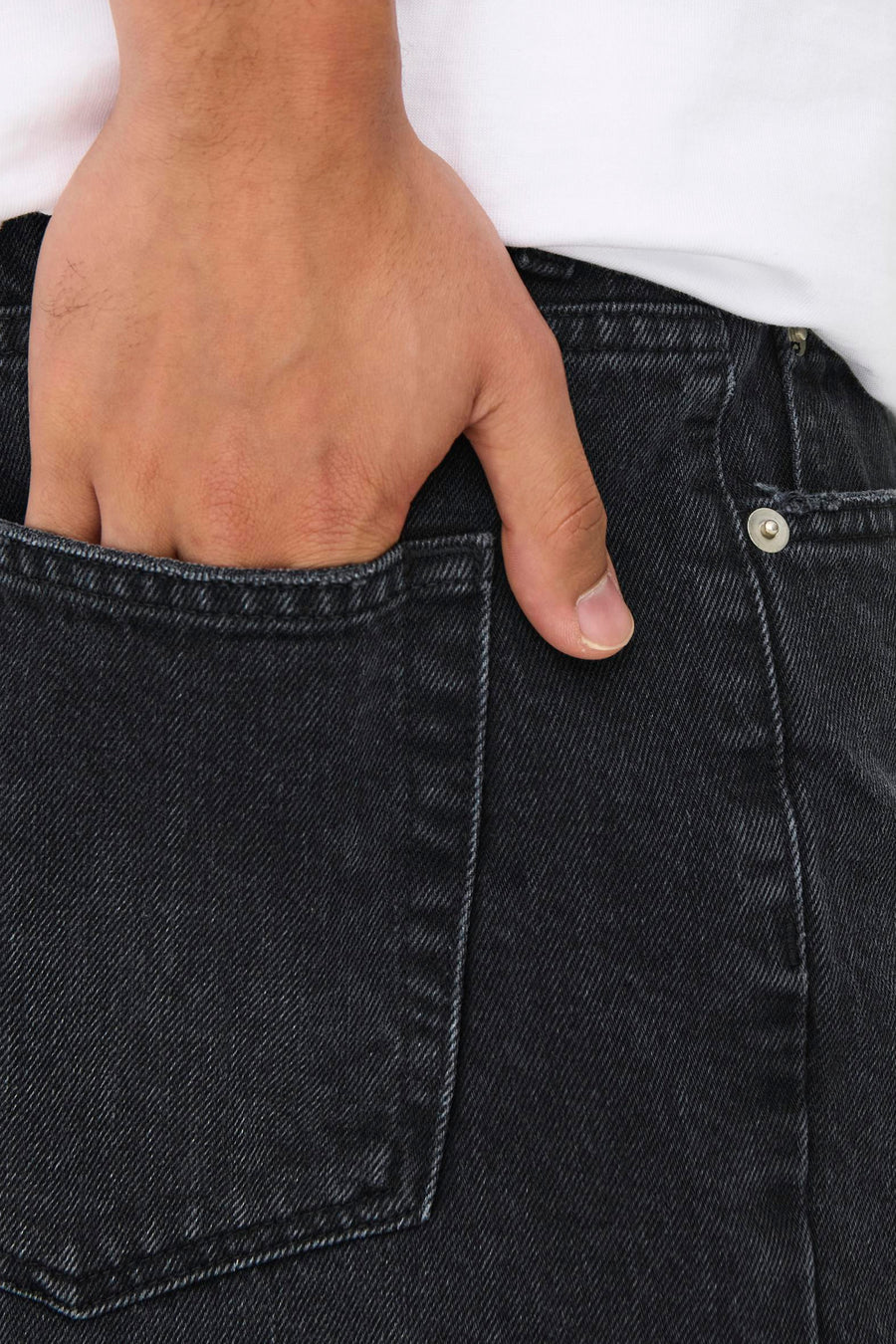Short en jean en denim noir ONLY & SONS® avec une main dans la poche, gros plan.