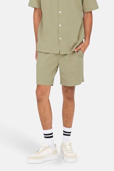 Short beige de ONLY & SONS, porté avec un chemisier beige, des baskets blanches et des chaussettes rayées.