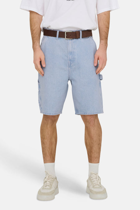 Lichtblauwe denim short van ONLY & SONS, met bruine riem, zilveren gesp en gedragen met wit T-shirt en crèmekleurige sneakers.